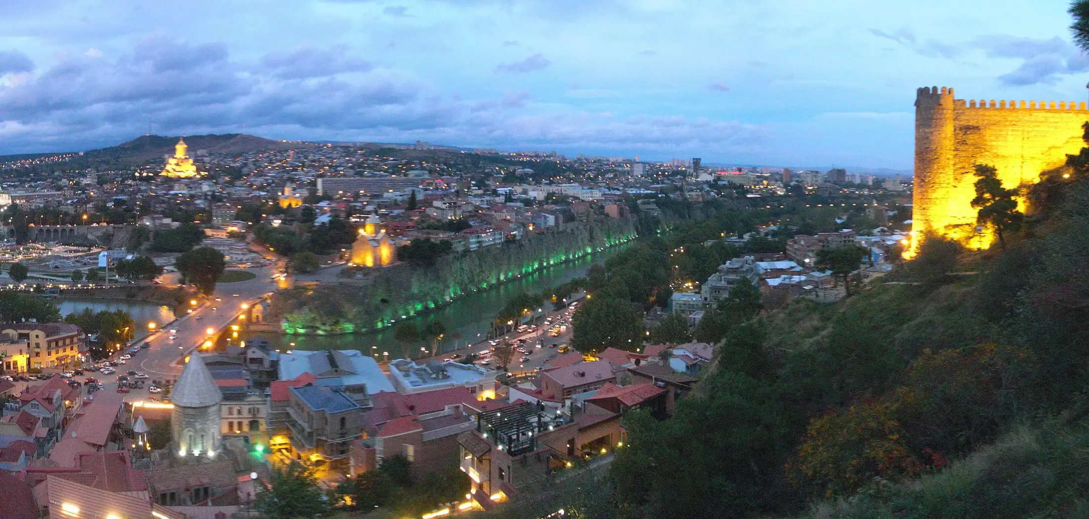 Old Tbilisi at dusk: Narikala fortress lit up above the Mtkvari river, Metekhi church and the Holy Trinity Cathedral